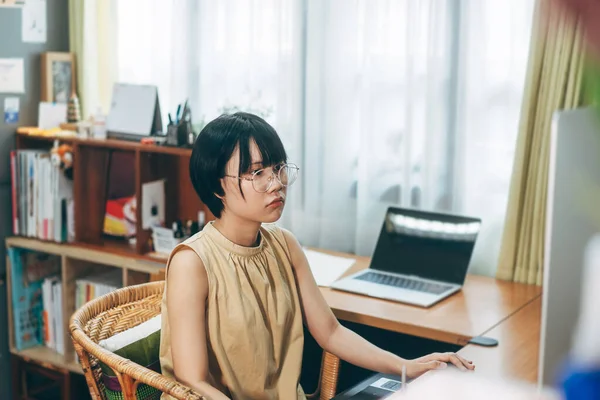 Young adult asian woman stay and work from home office concept. Female using computer for career via internet online. Background with computer indoor on day.