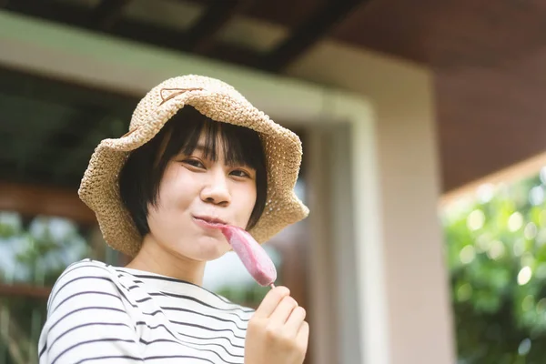 夏休みに幸せなアジアのティーンエイジャーの女性 自宅の屋外庭園でアイスクリームを食べリラックスしてください 女の子は白いシャツと国の帽子のスタイルを着用 — ストック写真
