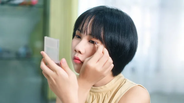 Portrait of single stills wellness lifestyle ready for day concept. Young adult asian woman makeup and face skin care before mirror in dress room at home.