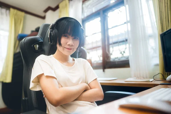 Young adult asian woman stay at home concept. She wear headphone listen online streaming music via internet. Freelance job business on day at house workplace.