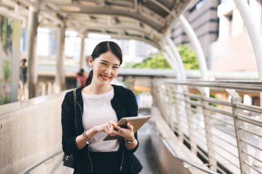 Asyalı bir kadın için çalışan genç bir iş adamı portresi. Güzel yüzlü kamera ve çekici bir gülümseme. El ele tutuşmak dijital tablet ve şık bir yaşam tarzı. Gün içinde kopyalama alanı olan arkaplan.