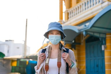 Portre mutlu genç Asyalı kadın sırt çantalı gezgin Corona virüsü veya covid-19 için yüz maskesi takıyor. Şehir yaşam tarzı konseptinde seyahat eden insanlar. Bangkok, Tayland