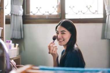 Bekar portresi sağlıklı yaşam tarzını gündüz konseptine hazırlar. Genç Asyalı kadın makyajı ve yüz derisi aynanın önünde evdeki elbise odasında.. 