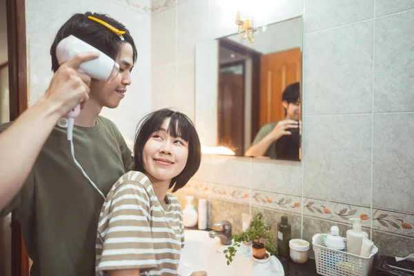 若い大人のアジアのカップルの男性と女性は ヘアドライヤーが吹いて髪をドレッシング 一緒に浴室で自宅でケア アジア様式の客室の背景 — ストック写真