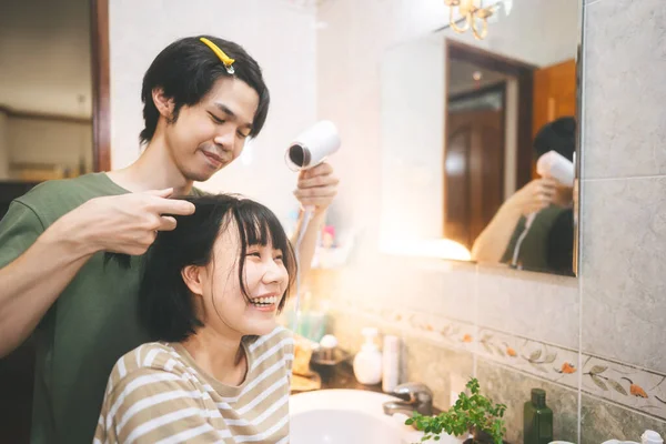 若い大人東南アジアの恋人カップル男と女性はヘアドライヤーが吹いて髪をドレッシング 幸福の関係ケア一緒に自宅でバスルーム — ストック写真