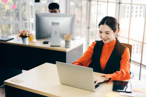 Portrait of happy smile office business asian salary woman. Workplace with document and computer. She working on laptop. Background with window light.