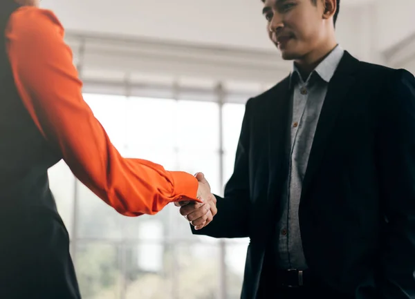 Asian adult business man and woman partner handshake together after suscessful with corporate teamwork. Greeting symbol body language. Background in marketing office.