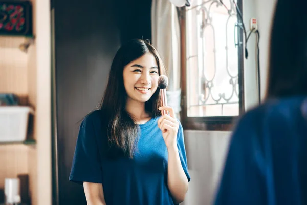 Portrait of single stills wellness lifestyle ready for day concept. Young adult asian woman makeup and face skincare before mirror in dress room at home.