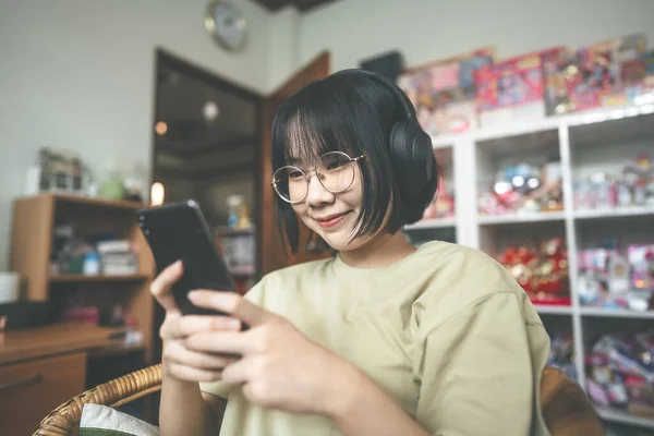 家庭のコンセプトで人々の幸せなライフスタイルの満足 若い大人のアジアの女性は ヘッドフォンを着用音楽を聞き デジタル社会通信のためのスマートフォンを使用してリラックス — ストック写真