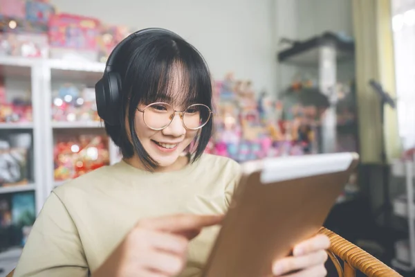 家庭のコンセプトで人々の幸せなライフスタイルの満足 若い大人のアジアの女性は ヘッドフォンを着用音楽を聞き 社会的コミュニケーションのためのデジタルタブレットを使用してリラックス — ストック写真
