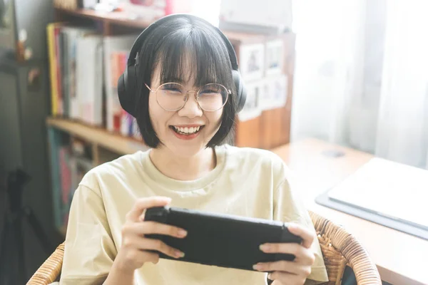 オタクスタイルの若い大人のアジアのゲーマーの女性は眼鏡を着用し ヘッドフォンはオンラインゲームをプレイします 勝利気分のための競争 家庭での幸せな人々のレジャーライフスタイル — ストック写真