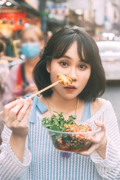 人々は旅行やストリートフードの概念を食べる 幸せな若いです大人アジア料理女性保持スパイシーなグリルイカで東南アジア中華街市場 — ストック写真