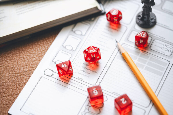 Role playing tabletop and board games hobby concept. D20 dice place on character sheets for create begin fantasy and adventure. Background with book and miniatures.