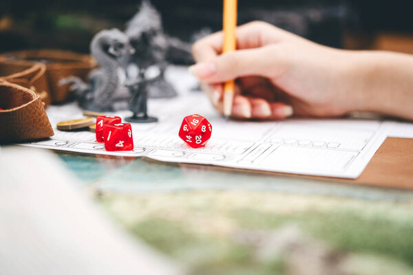 Role playing tabletop and board games hobby concept. Focus on dice d20. Blur background with hand writing for create story and monster miniatures.
