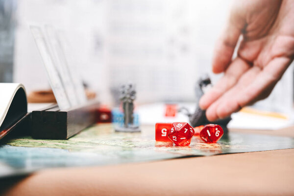 Role playing tabletop and board games hobby concept. Focus on dice d20. Blur background with hand and monster miniatures.
