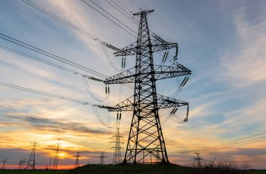 Gün batımında elektrik direkleri ve doymuş güzel gökyüzü. dağıtım, iletim ve elektrik tüketimi