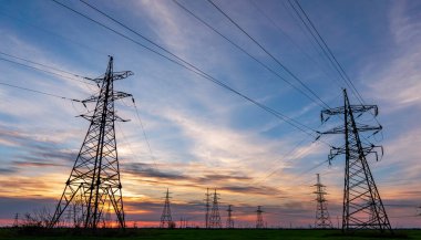 Gün batımında elektrik direkleri ve doymuş güzel gökyüzü. dağıtım, iletim ve elektrik tüketimi