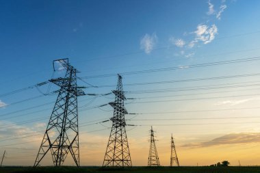 Gün batımında elektrik direkleri ve doymuş güzel gökyüzü. dağıtım, iletim ve elektrik tüketimi