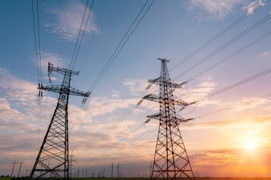 Gün batımında elektrik direkleri ve doymuş güzel gökyüzü. dağıtım, iletim ve elektrik tüketimi