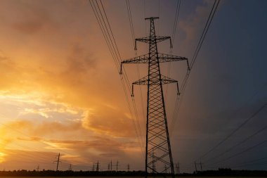 Gün batımında elektrik direkleri ve doymuş güzel gökyüzü. dağıtım, iletim ve elektrik tüketimi