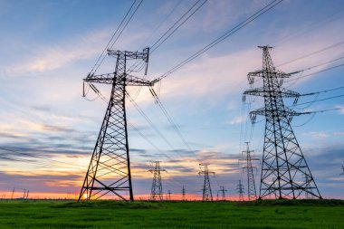 Gün batımında elektrik direkleri ve doymuş güzel gökyüzü. dağıtım, iletim ve elektrik tüketimi