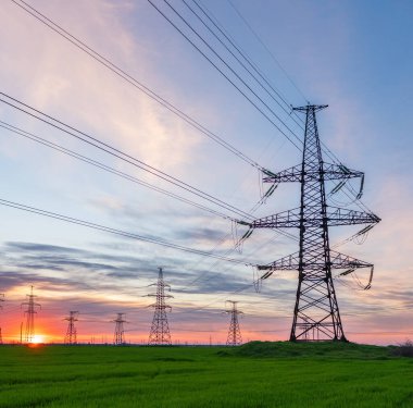 Gün batımında elektrik direkleri ve doymuş güzel gökyüzü. dağıtım, iletim ve elektrik tüketimi