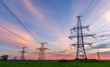 Gün batımında elektrik direkleri ve doymuş güzel gökyüzü. dağıtım, iletim ve elektrik tüketimi