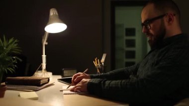 Çalışan adam masada oturuyor. İskandinav çalışma alanı. Sınav için gece hazırlığı. Geceleri ders çalışmak. Çatı katı tasarımı.