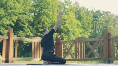 The man is training on the background of the forest. Exercises to strengthen neck muscles. Back view.