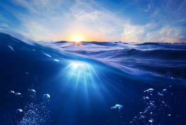 blue water surface with waves, sun rays, ripples.