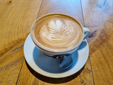 Güzel beyaz bir fincan kapuçino Kafedeki ahşap bir masa üzerinde kahve