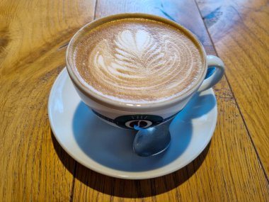 Güzel beyaz bir fincan kapuçino Kafedeki ahşap bir masa üzerinde kahve