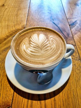 Güzel beyaz bir fincan kapuçino Kafedeki ahşap bir masa üzerinde kahve