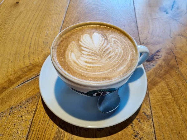 Güzel beyaz bir fincan kapuçino Kafedeki ahşap bir masa üzerinde kahve