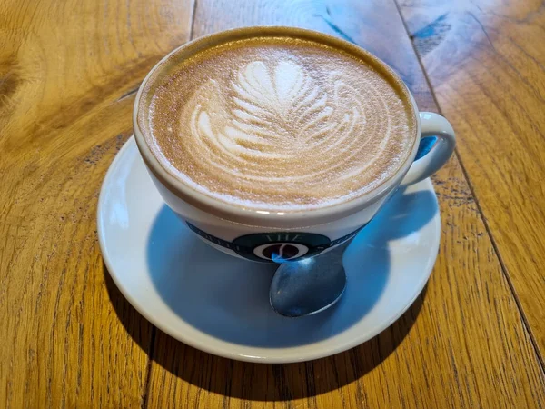 Güzel beyaz bir fincan kapuçino Kafedeki ahşap bir masa üzerinde kahve