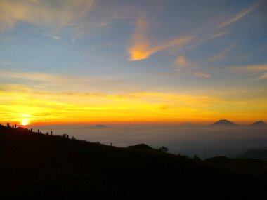 Bir dağın üzerinde güzel bir gün batımı ve arka planda dağlar