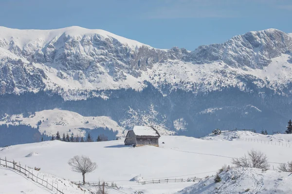 Eski bir ev ve arkasında Bucegi dağları olan kış manzarası. Transilvanya 'da Drakula' nın şatosu ve Karpatya dağları yakınlarındaki bir köyde.