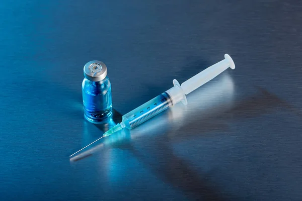 Mavi arka planda şırınga ve şişe