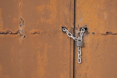 Paslı demir kapının üzerindeki gri renkli demir asma kilit.