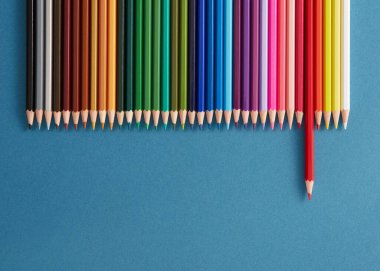 Mavi arkaplandaki bir satırdaki renkli kalemler.