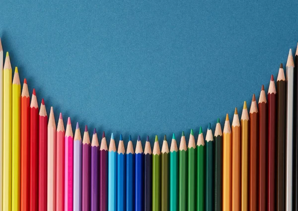 Pürüzsüz yatay desen mavi arkaplan üzerinde not, metin ve metin için kopyalama alanı olan bir dalgada düzenlenmiş renkli kalemler. 