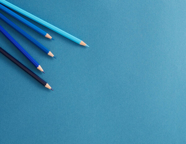 Flatlay photo of colored pencils on the background, stationery on an blue background