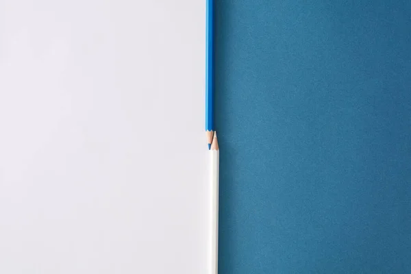 色彩斑斓的铅笔在白色和蓝色的通用双色调的纸张背景上 两只彩色钢笔 两声双色底色 顶部视图关闭 — 图库照片