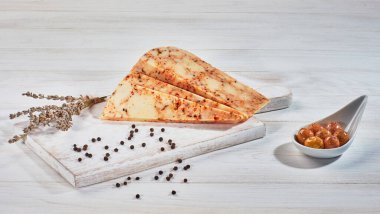 Ahşap kesme tahtasındaki dilimlenmiş peynirli otlar.