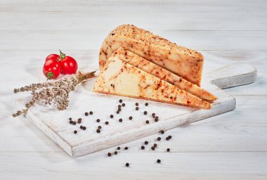 Ahşap kesme tahtasındaki dilimlenmiş peynirli otlar.