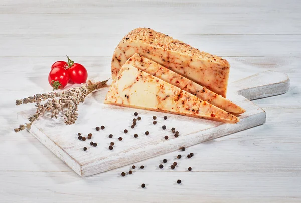 Ahşap kesme tahtasındaki dilimlenmiş peynirli otlar.