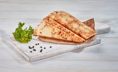 Ahşap kesme tahtasındaki dilimlenmiş peynirli otlar.