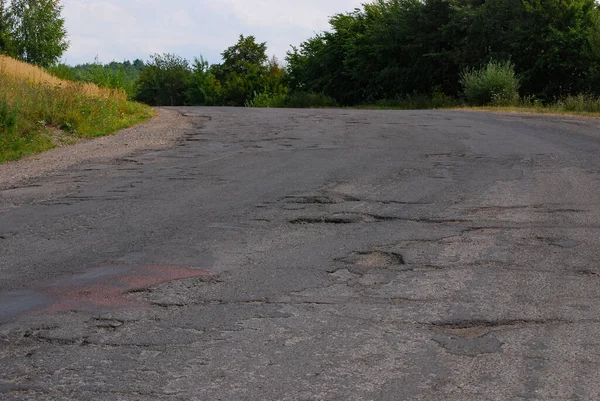 Hole in the road. Broken asphalt. Destroyed surface. Cracked road.