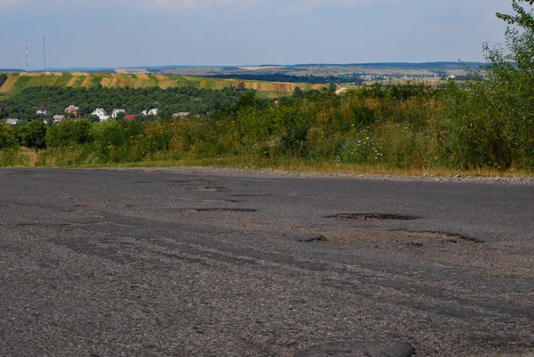 Hole in the road. Broken asphalt. Destroyed surface. Cracked road.