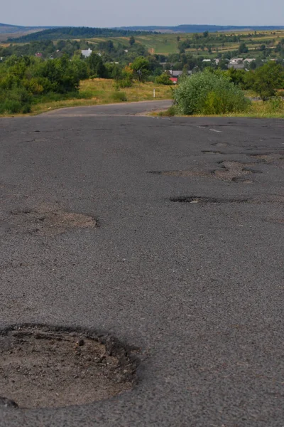 Hole in the road. Broken asphalt. Destroyed surface. Cracked road.